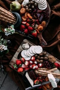 Top view of a rustic cheese platter featuring fruits, olives, and crackers.
